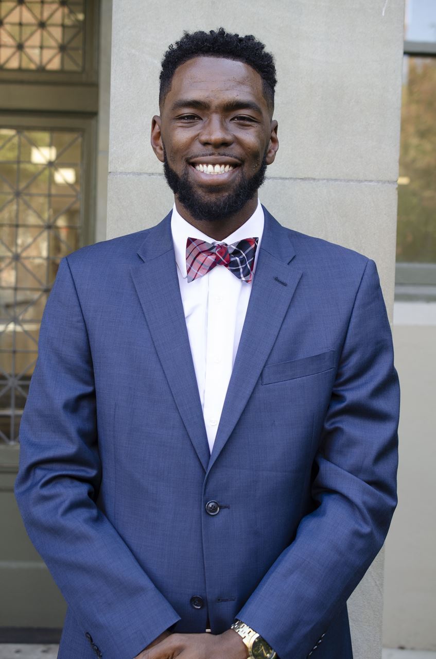 Photo of President Jason Dorsette in a dark blue suit and a plaid bowtie